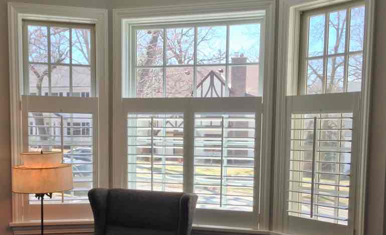 Half plantation shutters in living room bay window.